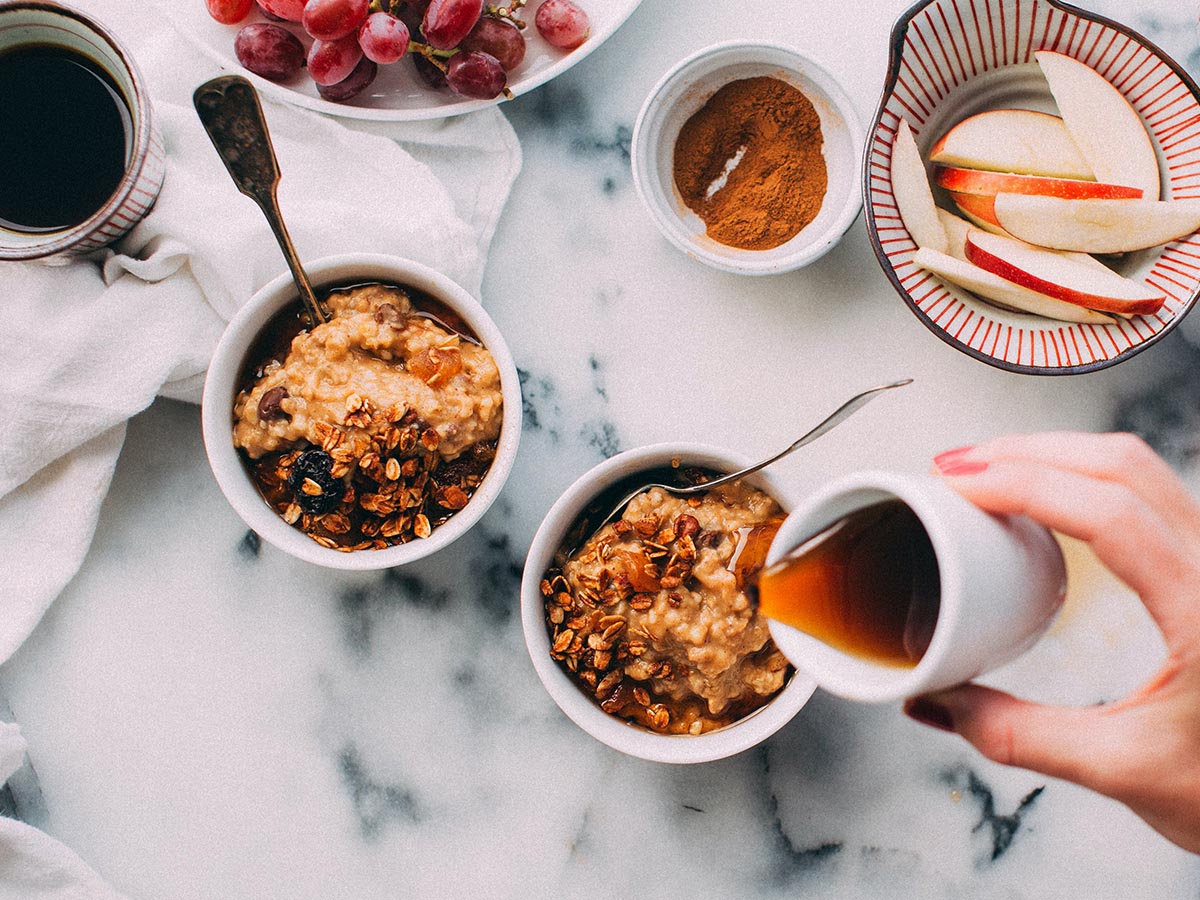 Woman pouring maple into a bowl of oatmeal